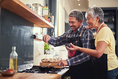 Buy stock photo Shot of a happy mature couple adding salt to a dish while cooking together at home