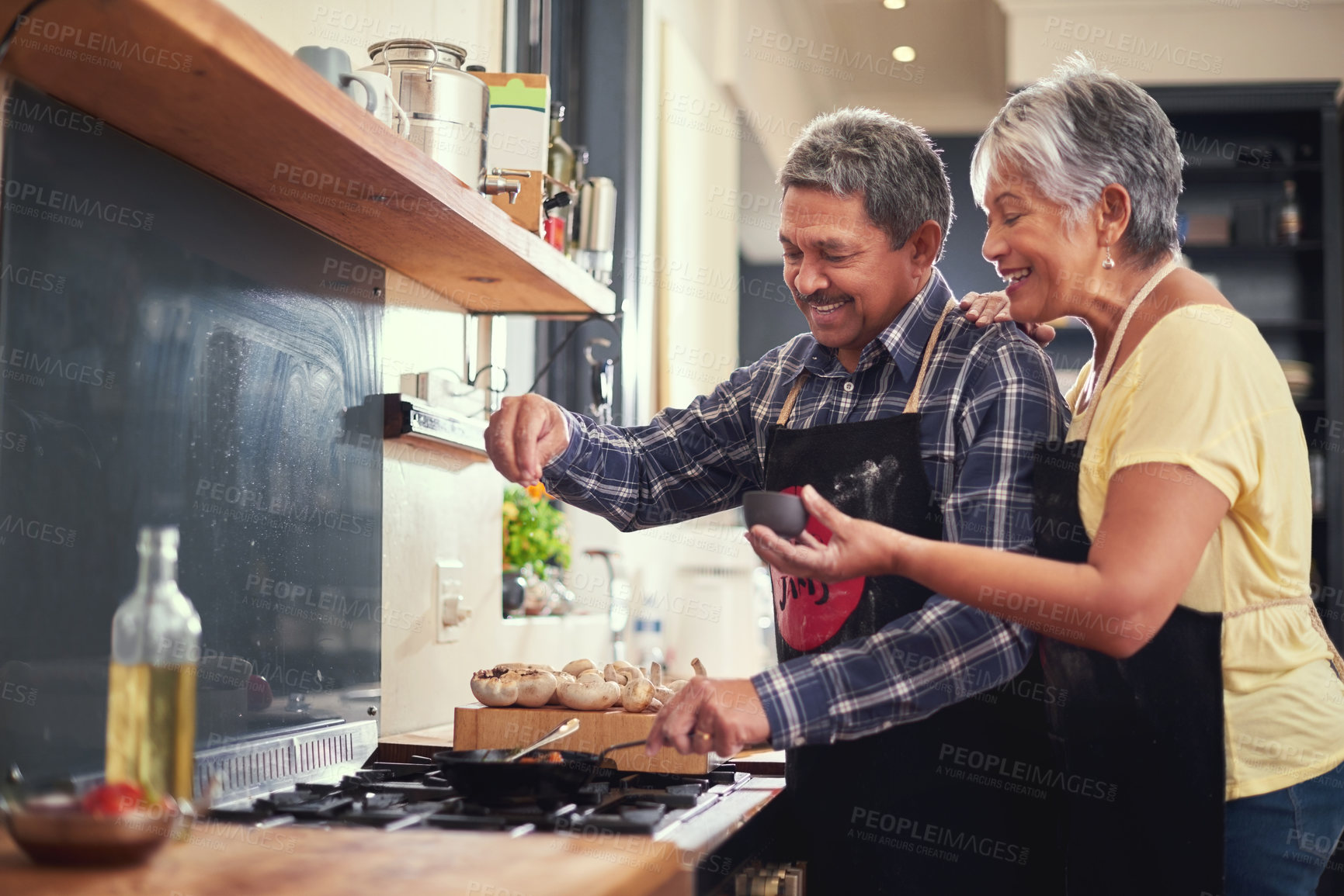 Buy stock photo Shot of a happy mature couple adding salt to a dish while cooking together at home