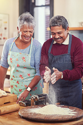 Buy stock photo Shot of a happy mature couple having fun together while preparing pasta from scratch at their home