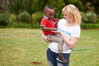 Buy stock photo Shot of a female volunteer carrying a little boy