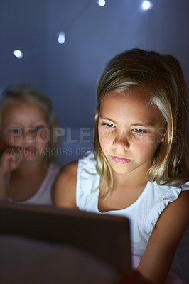 Buy stock photo Shot of two little girls using a digital tablet before bedtime