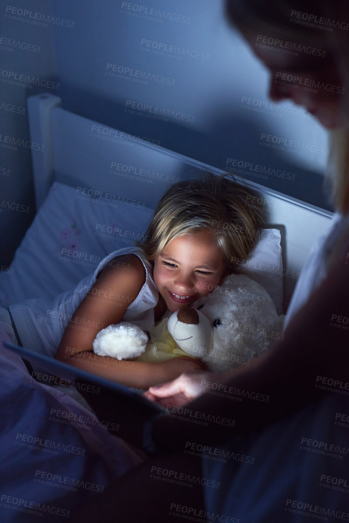 Buy stock photo Shot of a little girl and her mother using a digital tablet before bedtime