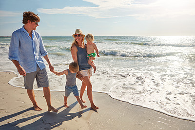 Buy stock photo Shot of a young family enjoying a summer day out at the beach