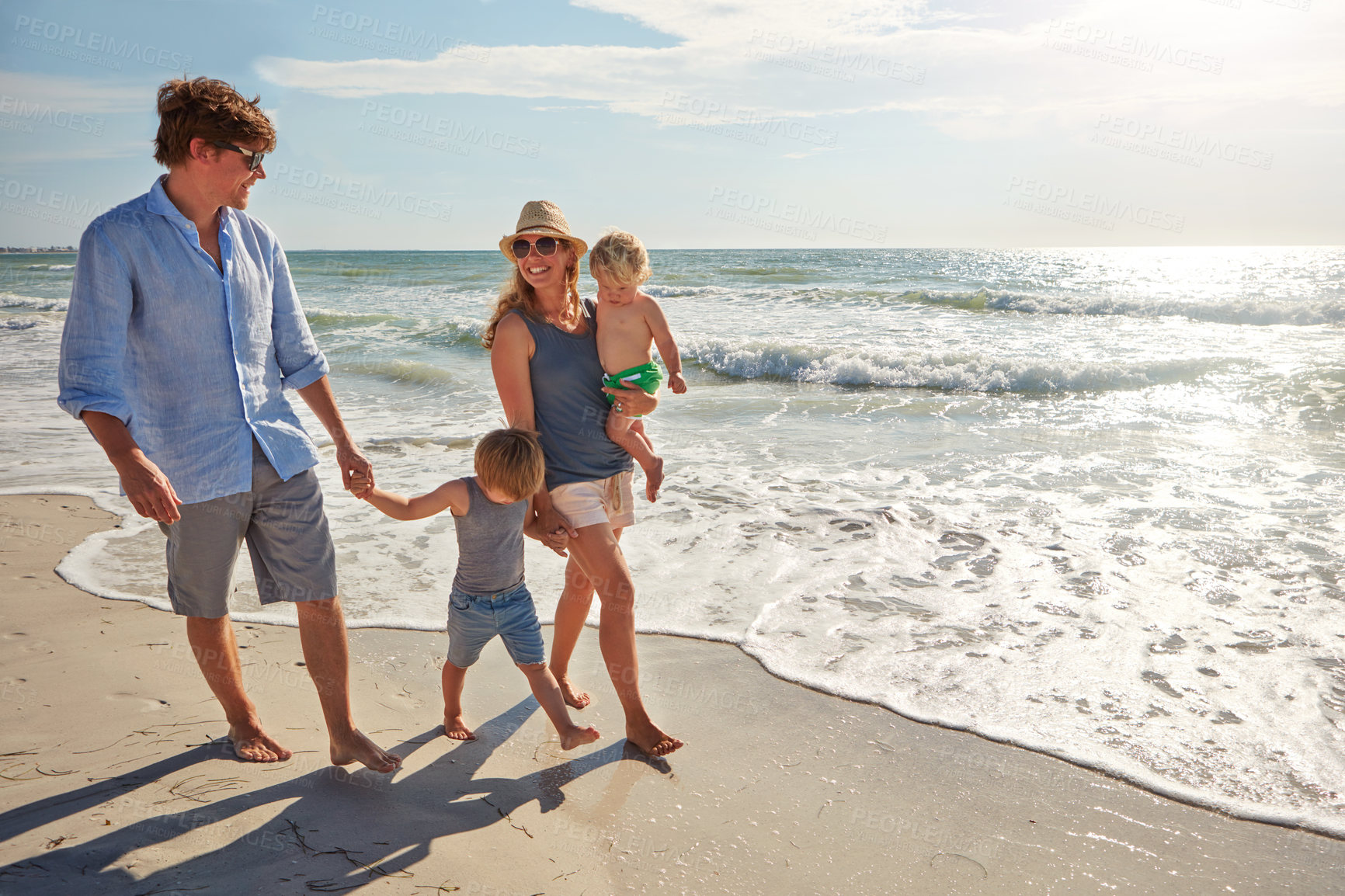 Buy stock photo Shot of a young family enjoying a summer day out at the beach