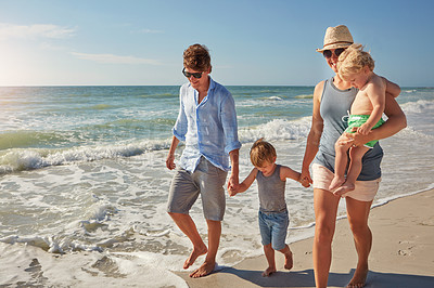 Buy stock photo Shot of a young family enjoying a summer day out at the beach