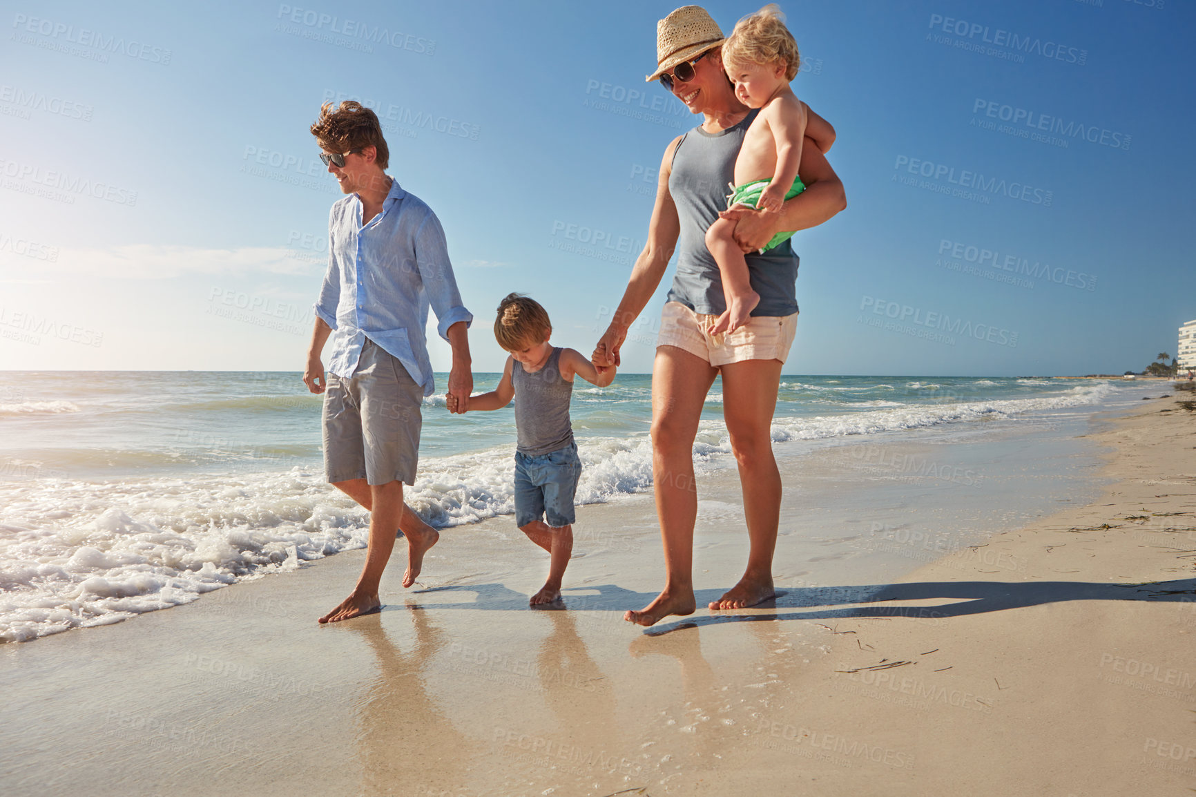 Buy stock photo Shot of a young family enjoying a summer day out at the beach