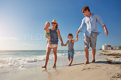 Buy stock photo Shot of a young family enjoying a summer day out at the beach