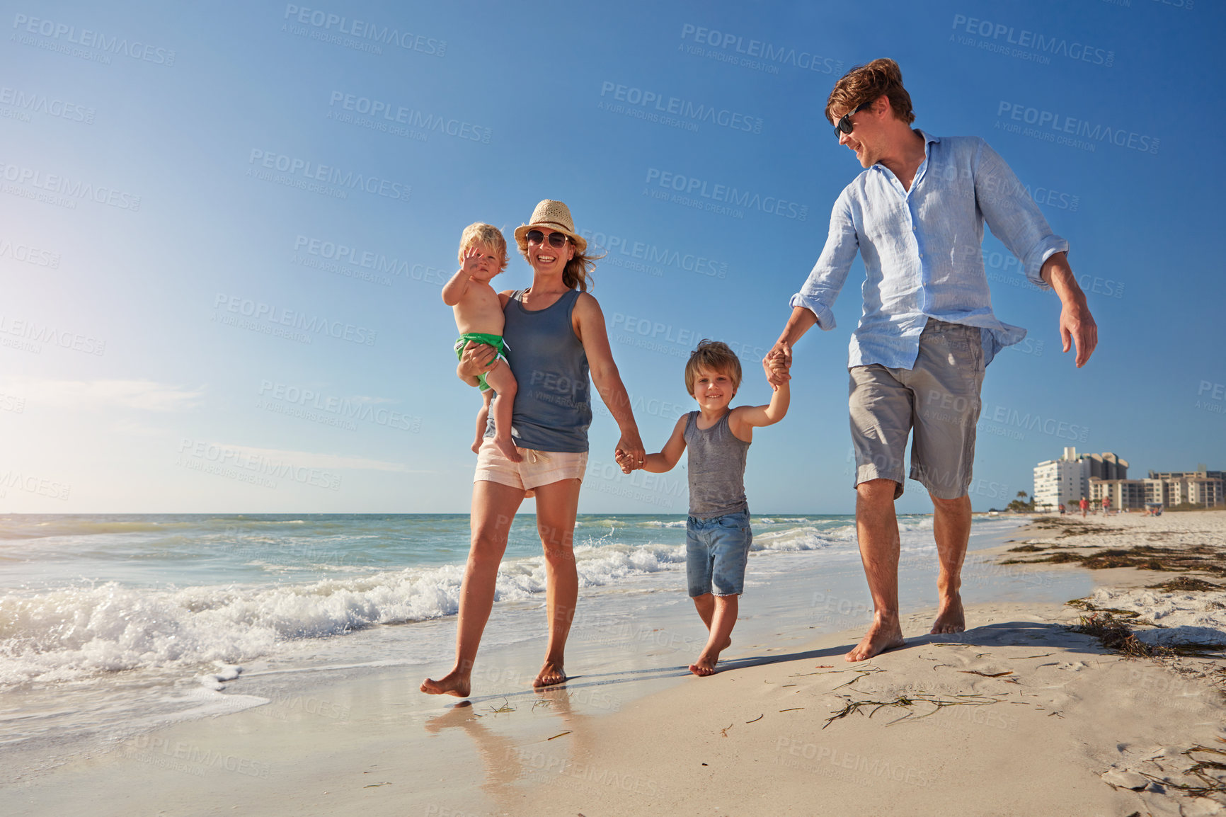 Buy stock photo Shot of a young family enjoying a summer day out at the beach