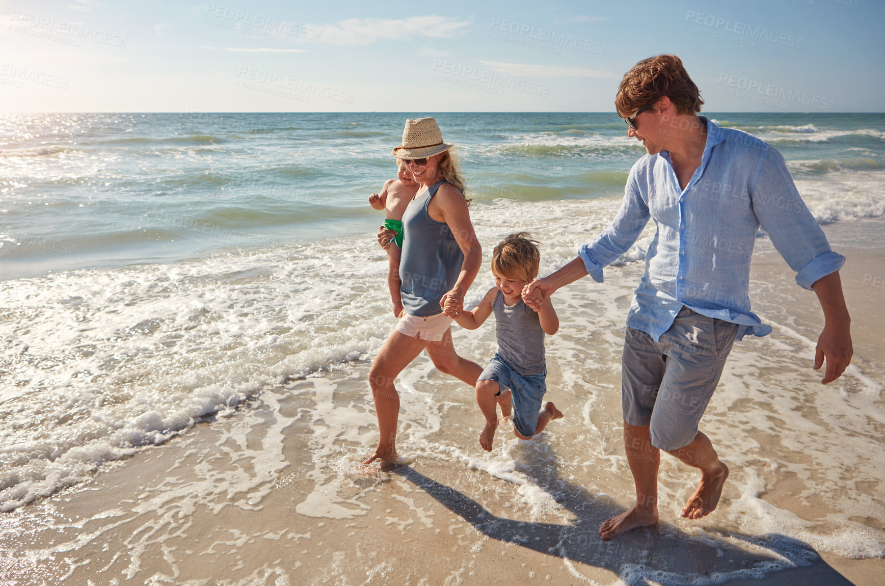 Buy stock photo Shot of a young family enjoying a summer day out at the beach