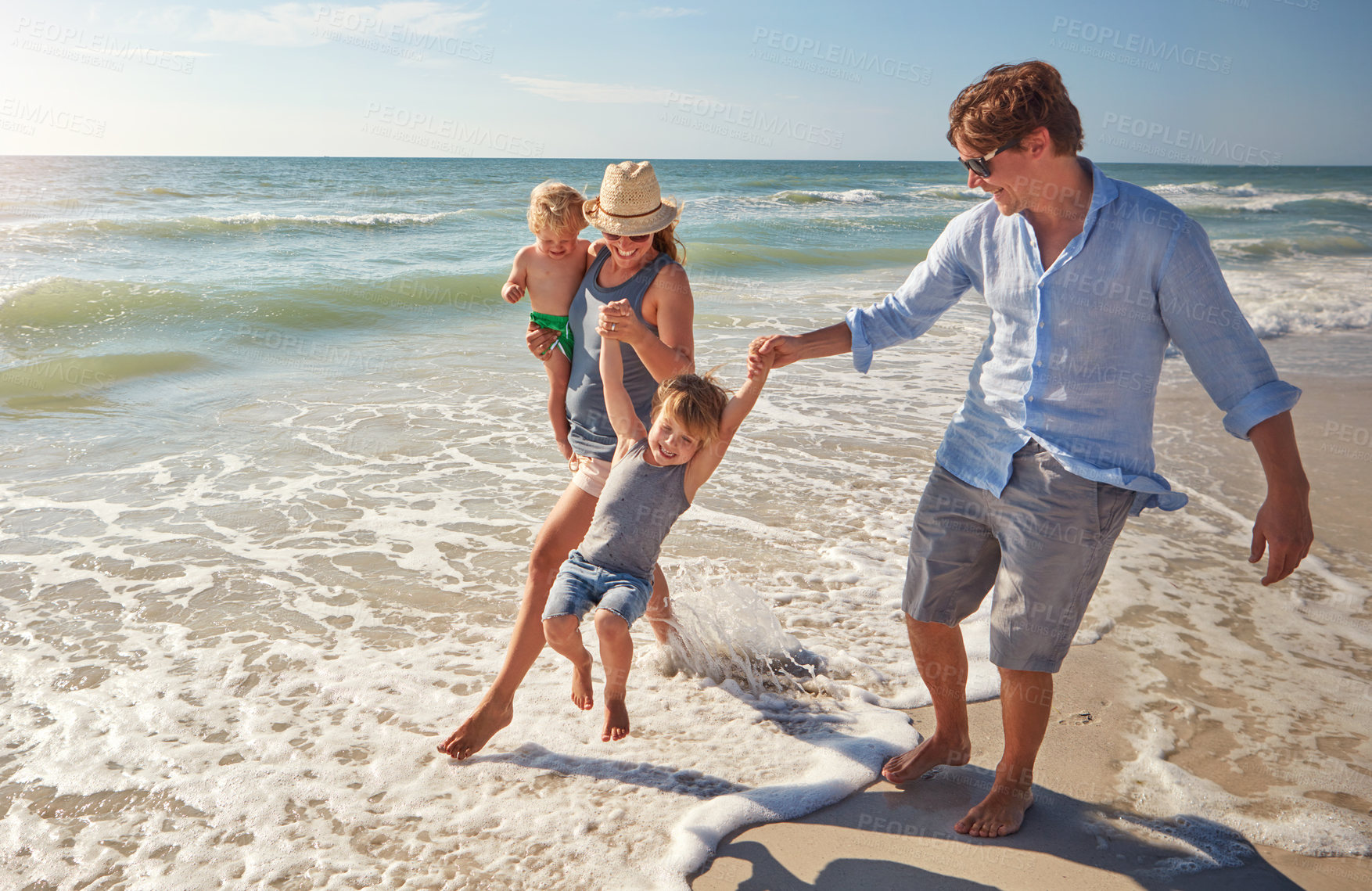 Buy stock photo Shot of a young family enjoying a summer day out at the beach