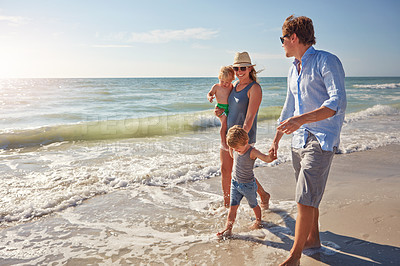 Buy stock photo Shot of a young family enjoying a summer day out at the beach