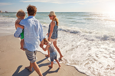 Buy stock photo Shot of a young family enjoying a summer day out at the beach