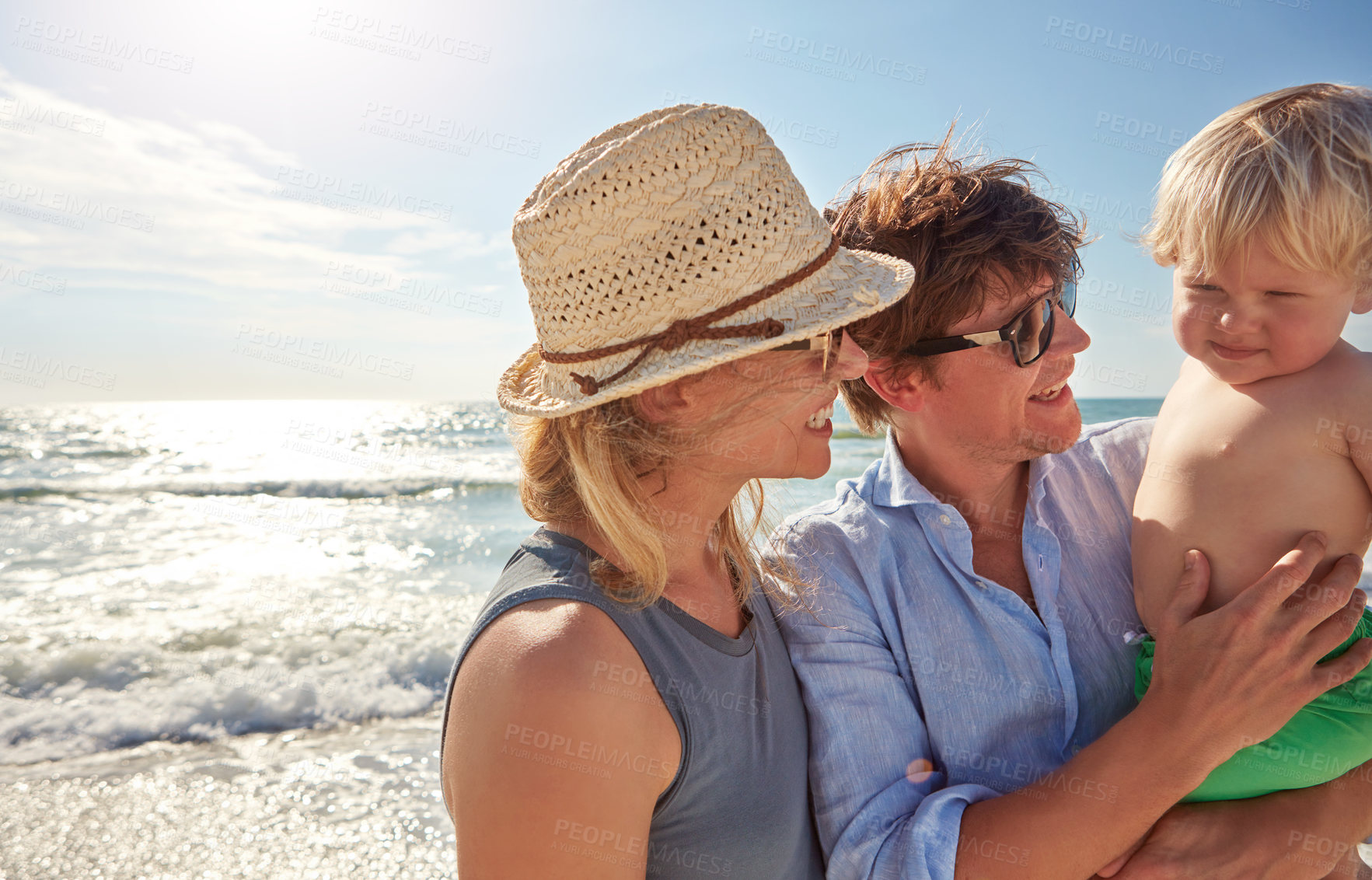 Buy stock photo Shot of a young family enjoying a summer day out at the beach