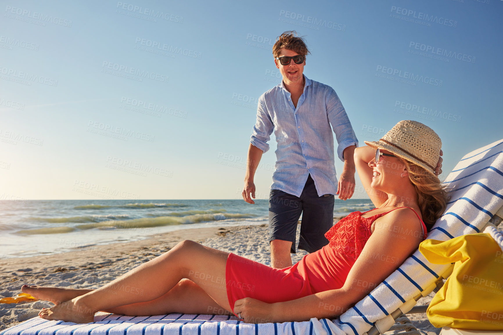 Buy stock photo Couple, vacation and woman on chair at beach for sunshine, travel and outdoor adventure together. Man, walking and smile with honeymoon by ocean for summer holiday, love or romantic getaway in Cancun
