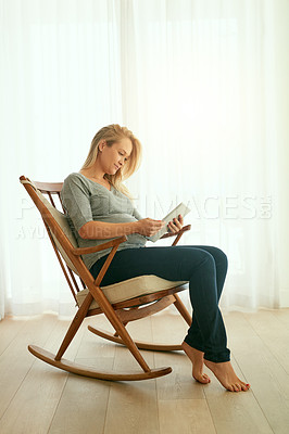 Buy stock photo Shot of a pregnant woman using her digital tablet while sitting on a rocking chair