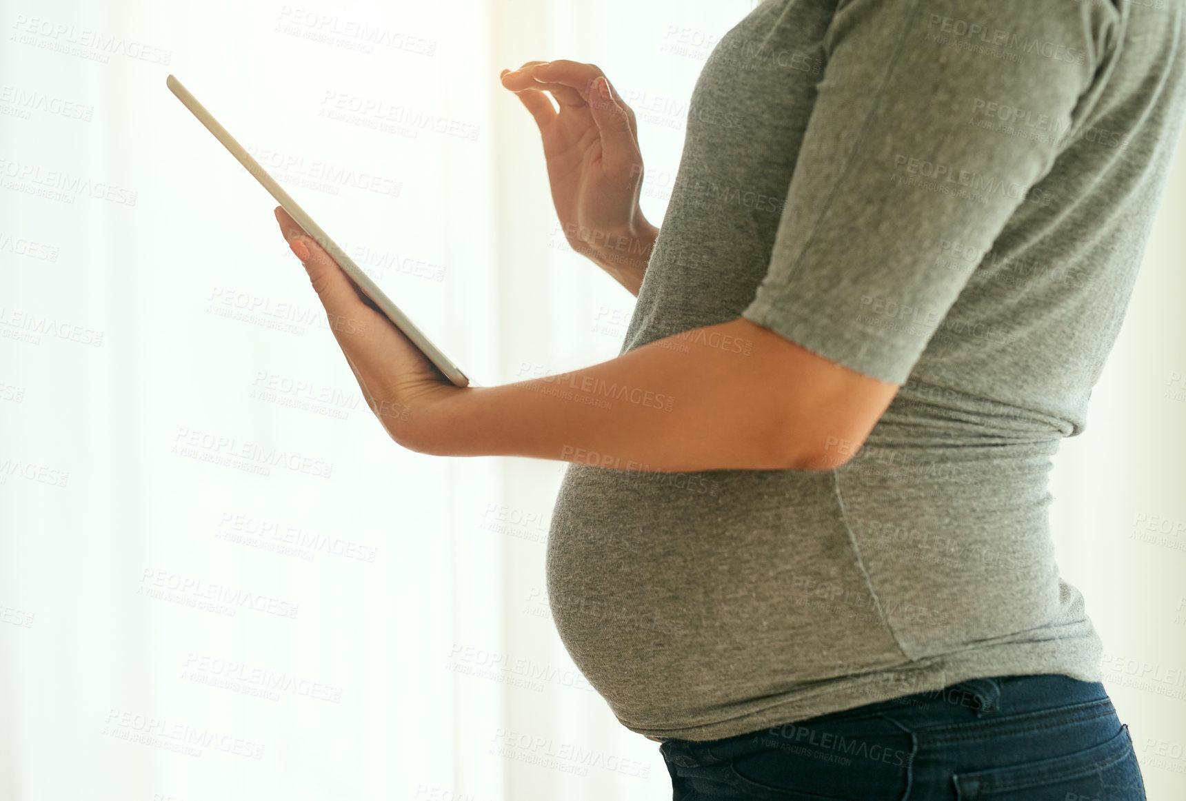 Buy stock photo Cropped shot of a pregnant woman using her digital tablet at home