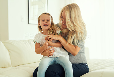 Buy stock photo Shot of a little girl sitting on her mother's lap at home