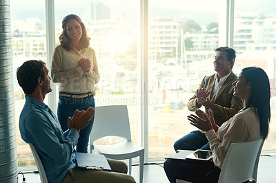 Buy stock photo Shot of a group of enthusiastic businesspeople applauding their colleague during a meeting in the office