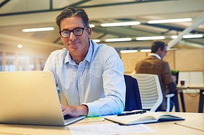 Buy stock photo Portrait of a happy hardworking businessman working on his laptop in the office