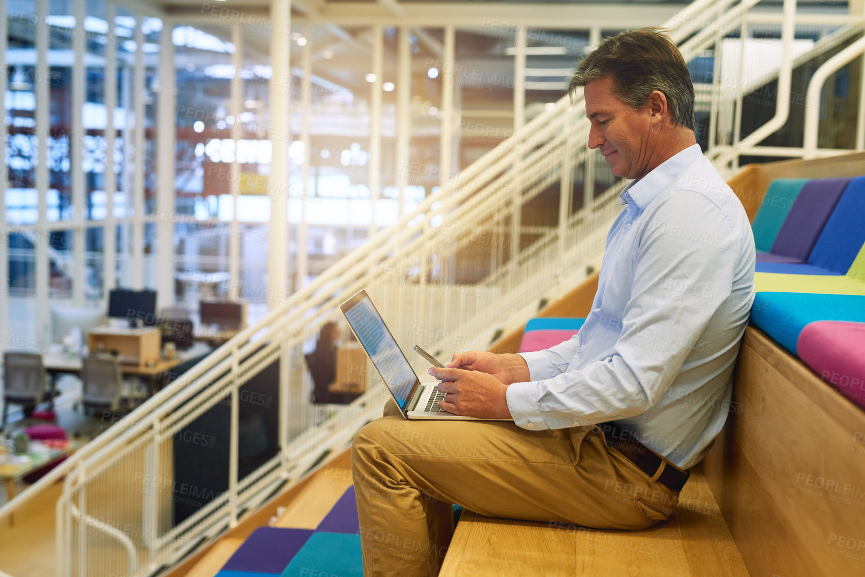 Buy stock photo Shot of a successful businessman using his laptop while sitting in a modern office