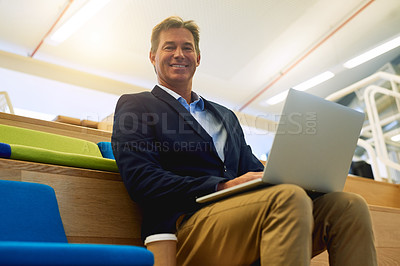 Buy stock photo Portrait of a successful businessman using his laptop while sitting in a modern office