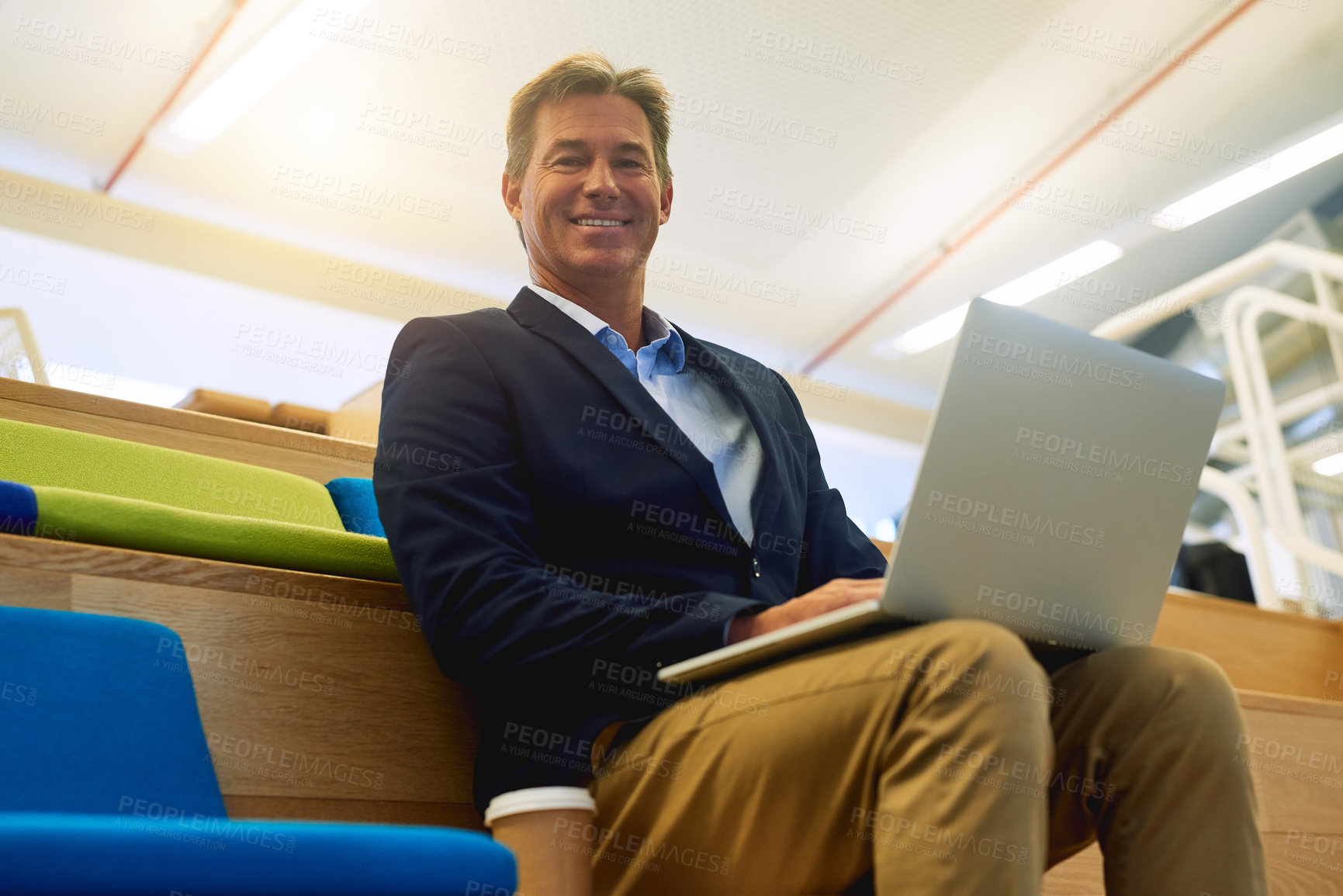 Buy stock photo Portrait of a successful businessman using his laptop while sitting in a modern office