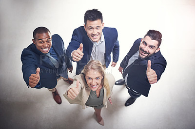 Buy stock photo High angle shot of a team of happy colleagues showing thumbs up together in the office