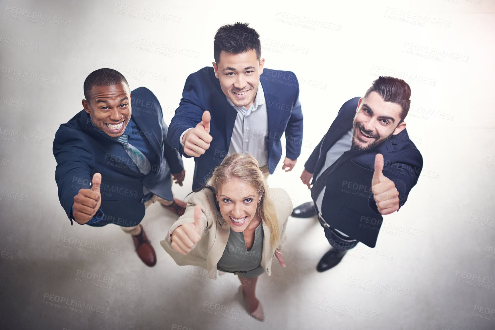 Buy stock photo High angle shot of a team of happy colleagues showing thumbs up together in the office