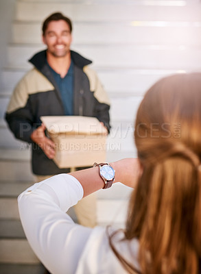 Buy stock photo Shot of a businesswoman checking the time on her watch as the courier arrives with a delivery
