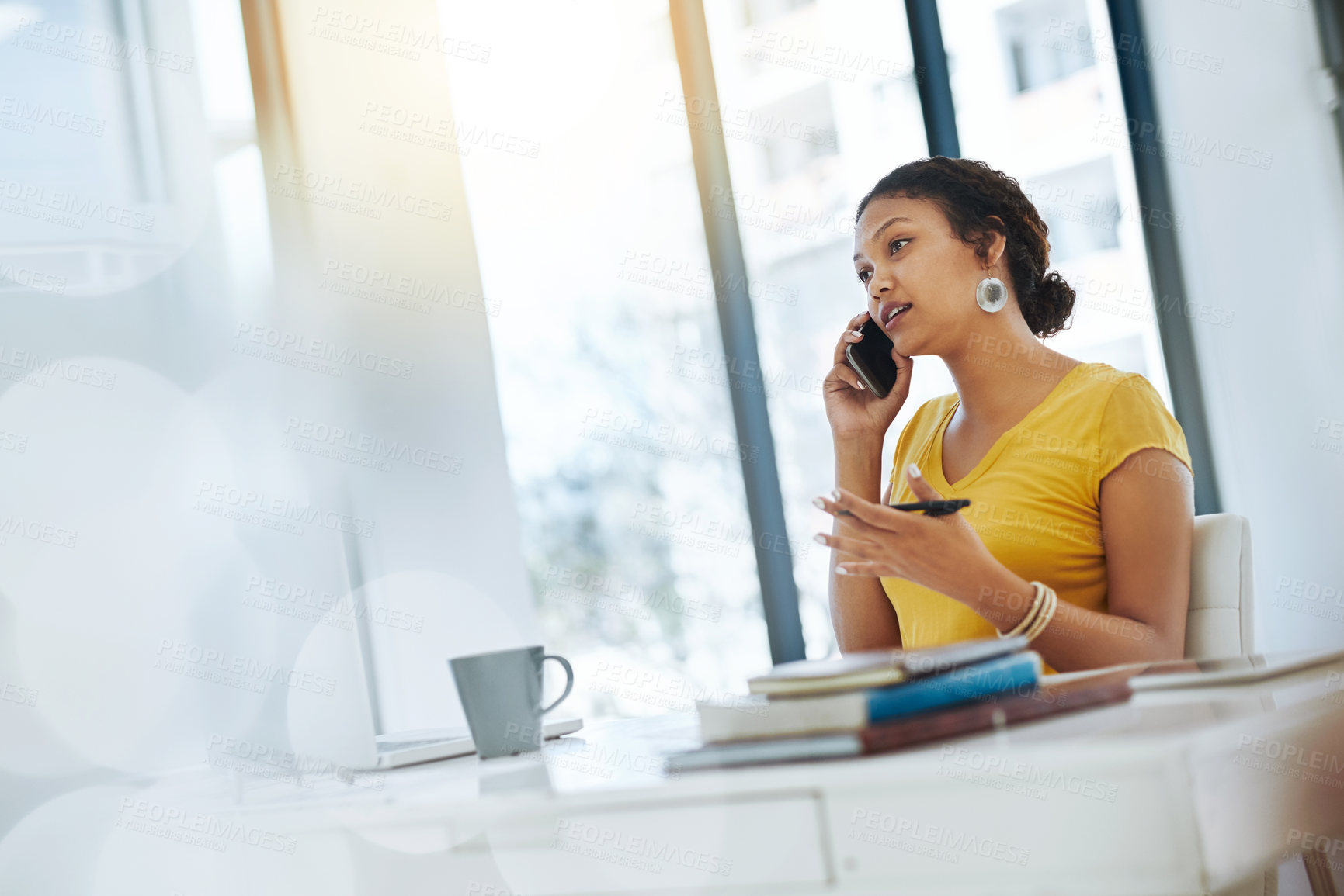 Buy stock photo Shot of a young designer talking on a cellphone while working in an office