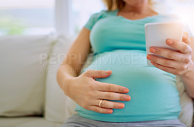 Buy stock photo Closeup shot of a pregnant woman texting on her cellphone at home