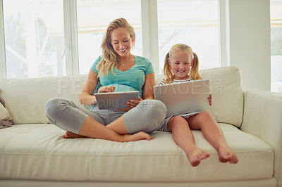 Buy stock photo Shot of a pregnant woman and her little daughter using digital tablets at home