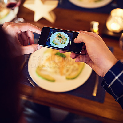 Buy stock photo Shot of an unrecognizable man taking a picture of food with his cellphone at the dining room table