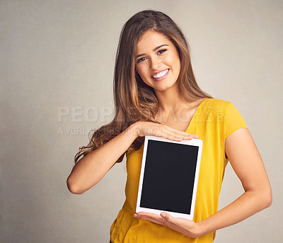 Buy stock photo Shot of an attractive young woman holding a digital tablet with a blank screen against a grey background