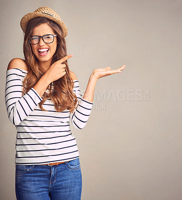 Buy stock photo Studio portrait of an attractive young woman presenting your copy space against a gray background
