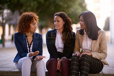 Buy stock photo Shot of a group of businesswomen having a discussion while seated outside on steps