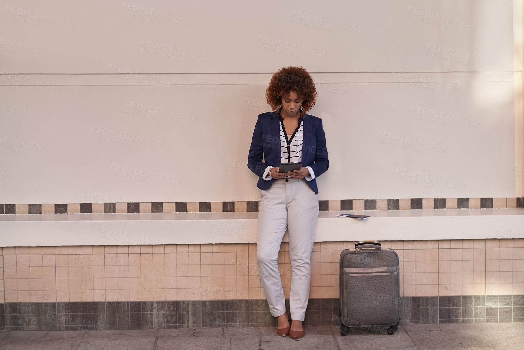 Buy stock photo Shot of a young businesswoman using her tablet while waiting for the train in the subway