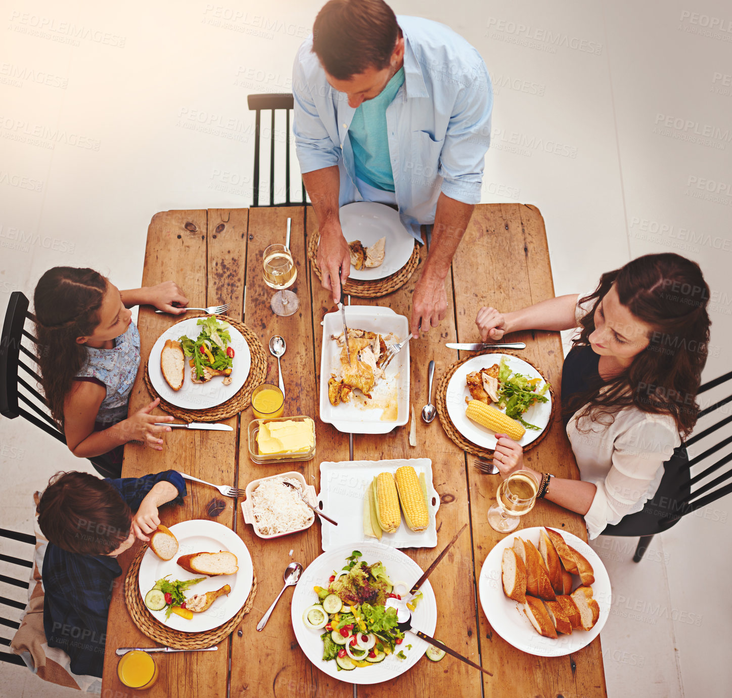 Buy stock photo High angle shot of a family eating homemade food around the dining room table