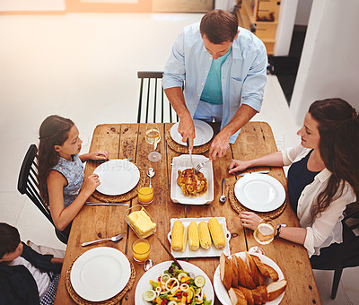 Buy stock photo High angle shot of a family eating  homemade food around the dining room table