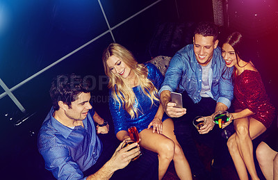 Buy stock photo Shot of a group of friends taking selfies on a mobile phone at a party