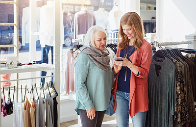 Buy stock photo Shot of a woman using her cellphone while out shopping with her mother