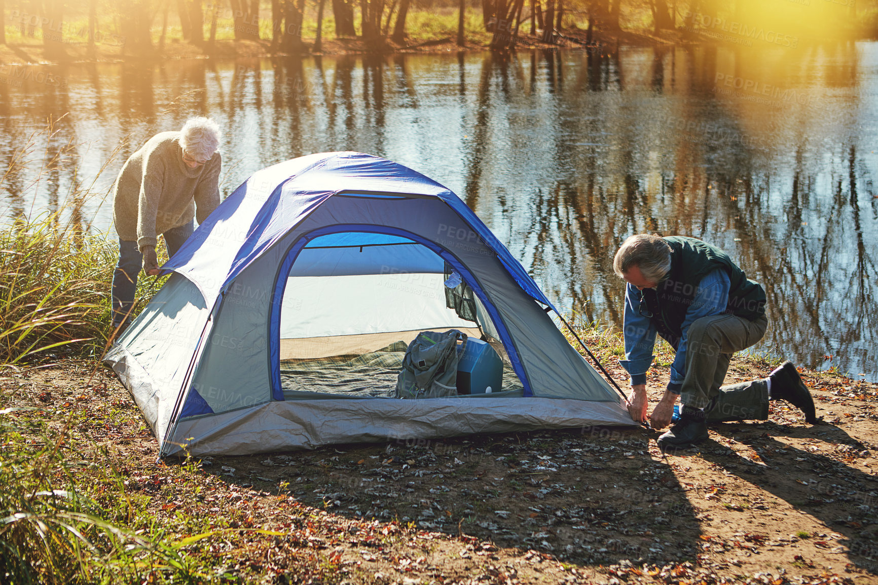 Buy stock photo Shot of a senior couple setting up a tent while camping in the wilderness