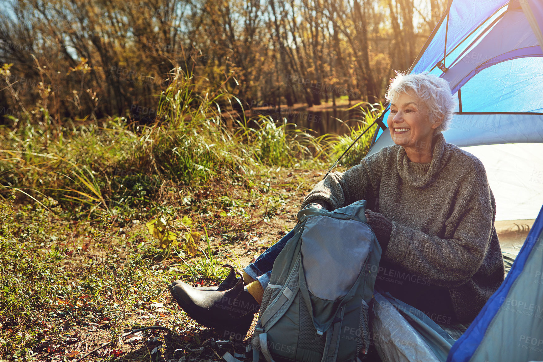 Buy stock photo Camp, mature woman and tent in wilderness, smile or outdoor to enjoy nature, freedom and sunshine. Retirement, hobby and morning at campsite, happy and healthy with wellness and relaxing natural view