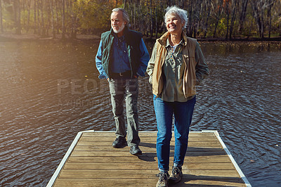 Buy stock photo Shot of a senior couple going for a walk on a jetty next to a lake