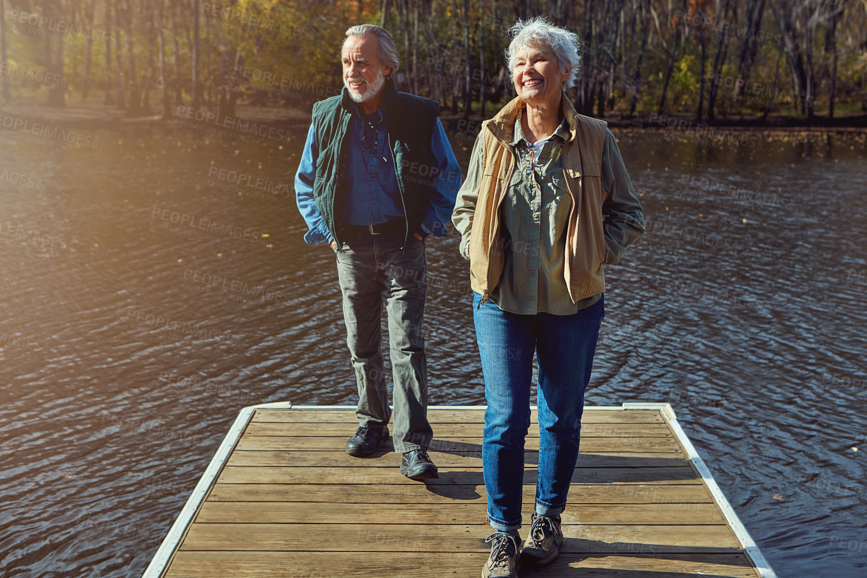 Buy stock photo Shot of a senior couple going for a walk on a jetty next to a lake