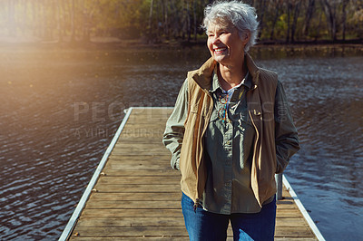 Buy stock photo Shot of a senior woman going for a walk on a jetty next to a lake