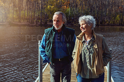 Buy stock photo Shot of a senior couple going for a walk on a jetty next to a lake