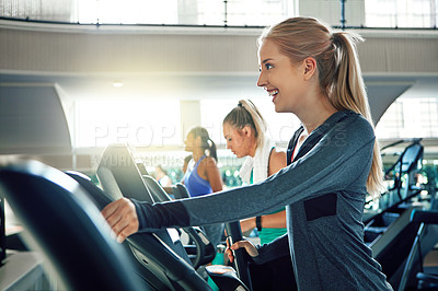 Buy stock photo Shot of a young woman working out with a machine at a gym