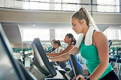 Buy stock photo Shot of a young woman working out with a machine at a gym