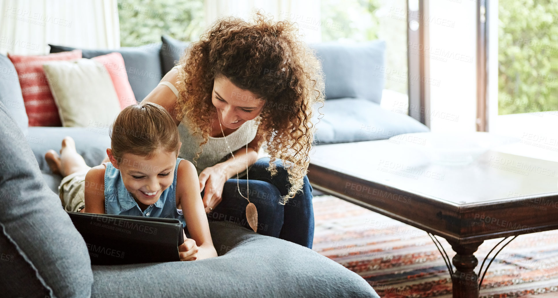 Buy stock photo Shot of a mother and her little daughter using a digital tablet together at home